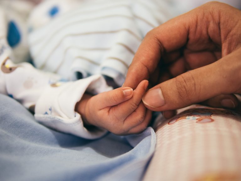 Adult holding infant hand